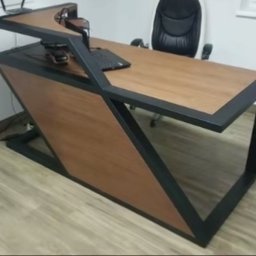 Weldingtiger - Nowoczesne biurko z drewnianym blatem i czarną metalową konstrukcją, widoczny komputer i słuchawki, w tle krzesło biurowe.