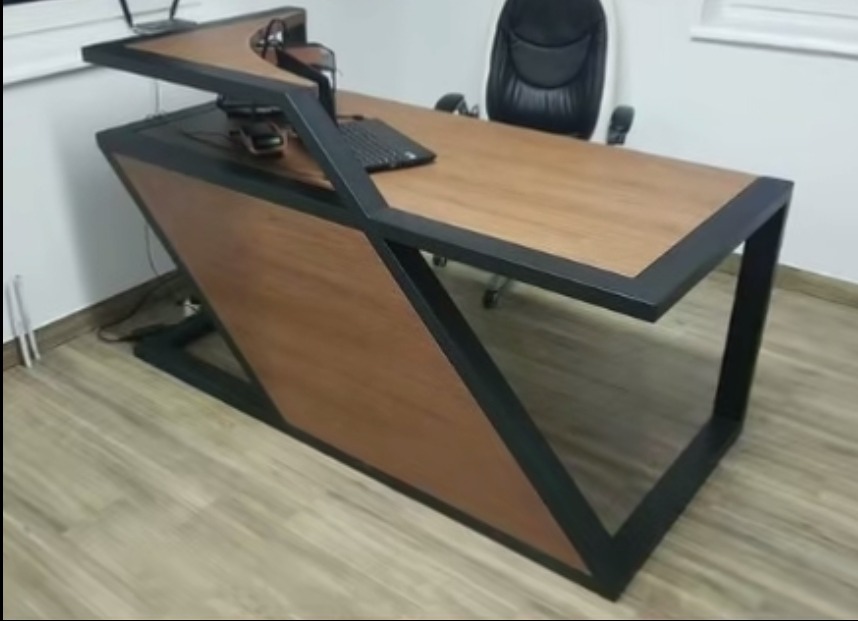 Nowoczesne biurko z drewnianym blatem i czarną metalową konstrukcją, widoczny komputer i słuchawki, w tle krzesło biurowe.