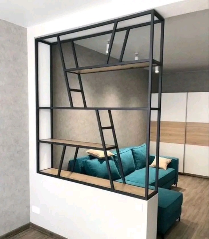 Nowoczesna szafa na wymiar z czarną metalową ramą i drewnianymi półkami, oddzielająca przestrzeń salonu z turkusową sofą.