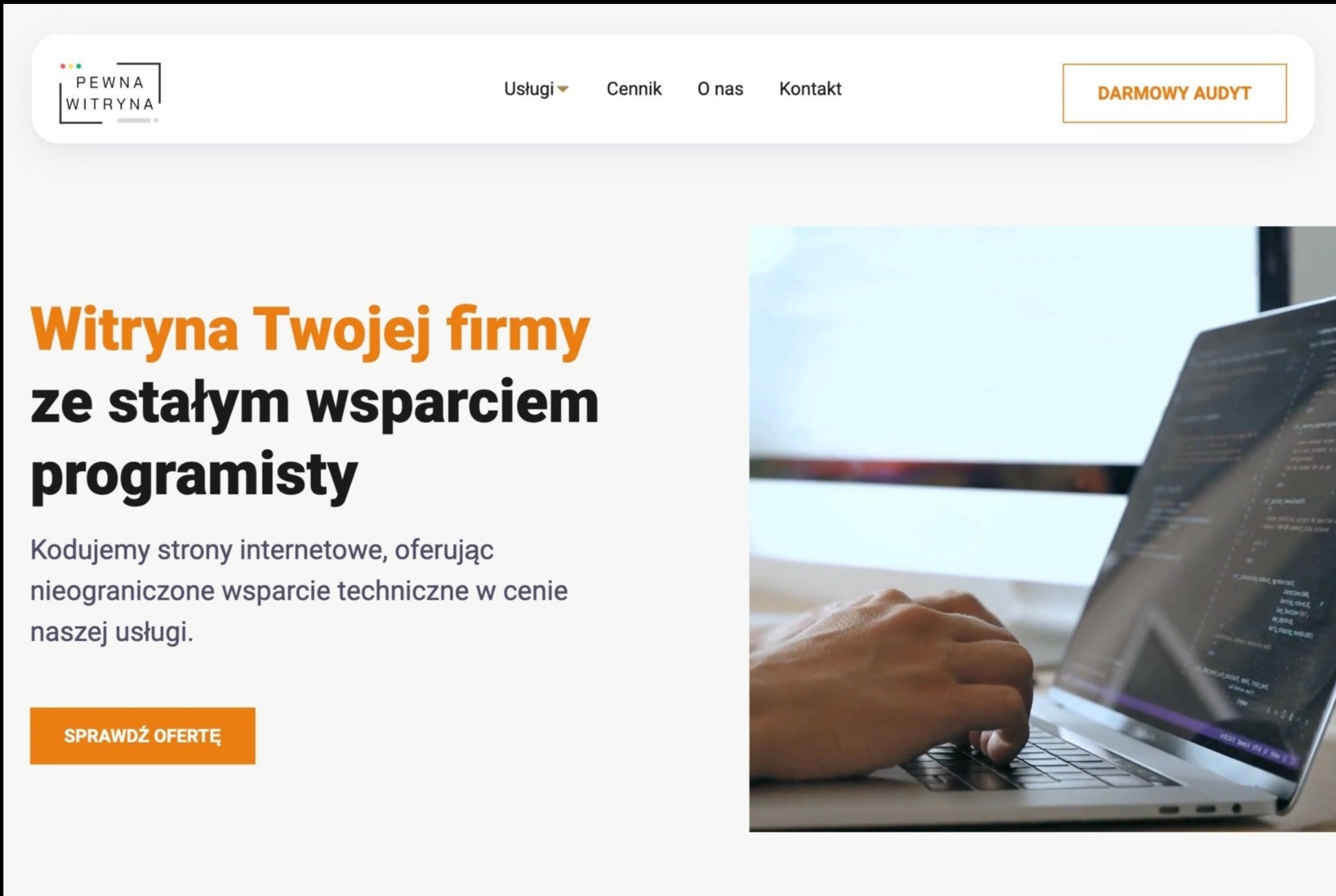Męskie dłonie piszą kod na laptopie, na ekranie widoczne linijki kodu, w tle biurko i monitor. Widok z boku, oświetlenie dzienne.