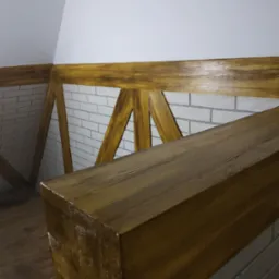 Drewniana balustrada antresoli z bejcowaną ramą i wypełnieniem w stylu rustykalnym, na tle ściany z białej cegły i drewnianej podłogi.