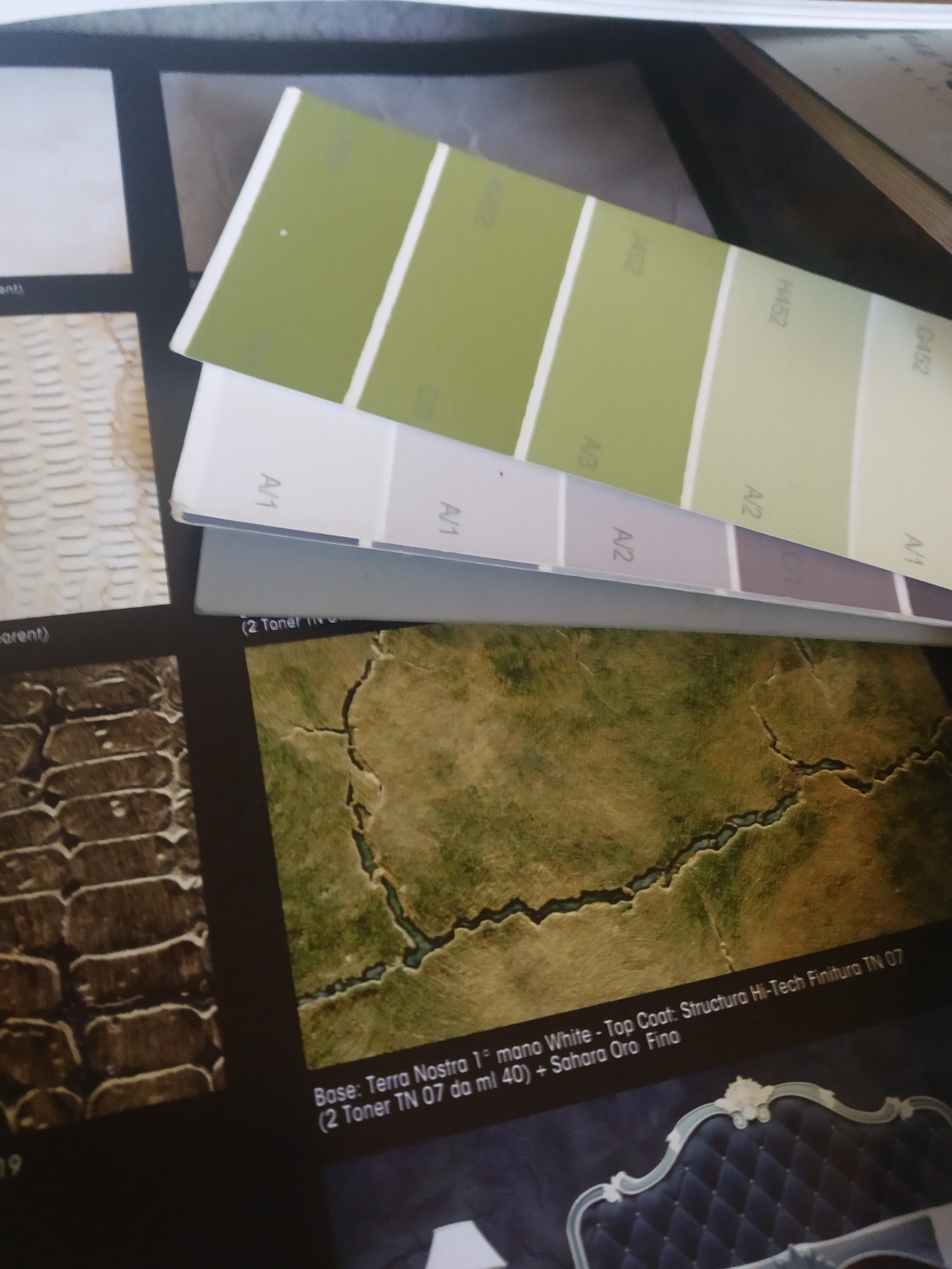 Paleta kolorów farb w odcieniach zieleni i szarości na tle próbek tekstur i wykończeń ścian.