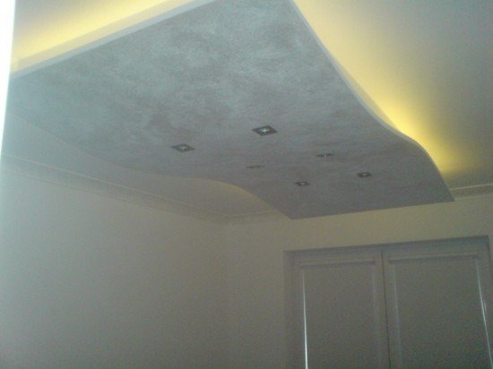 Podwieszany sufit z szarego betonu architektonicznego z wbudowanymi punktami świetlnymi, oświetlenie LED wzdłuż krawędzi, widok z dołu.