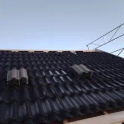 Montaż czarnej blachodachówki na nowym dachu, widoczne pakiety płytek i drewniane łaty pod konstrukcją.