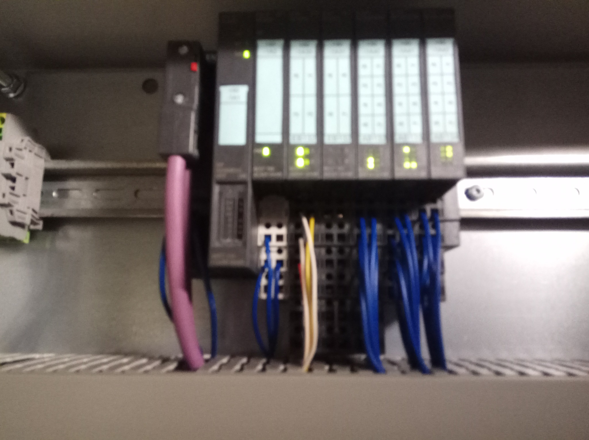 Panel sterowania z modułami elektronicznymi, widoczne podłączenia kablowe w kolorach niebieskim, białym, czerwonym i fioletowym oraz diody sygnalizacyjne.