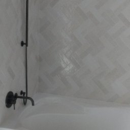 Yurii Drohomyretskyi KUB - Biała wanna z czarną armaturą i prysznicem na tle ściany wyłożonej jasnymi płytkami w jodełkę, tworząc minimalistyczny i nowoczesny wystrój łazienki.