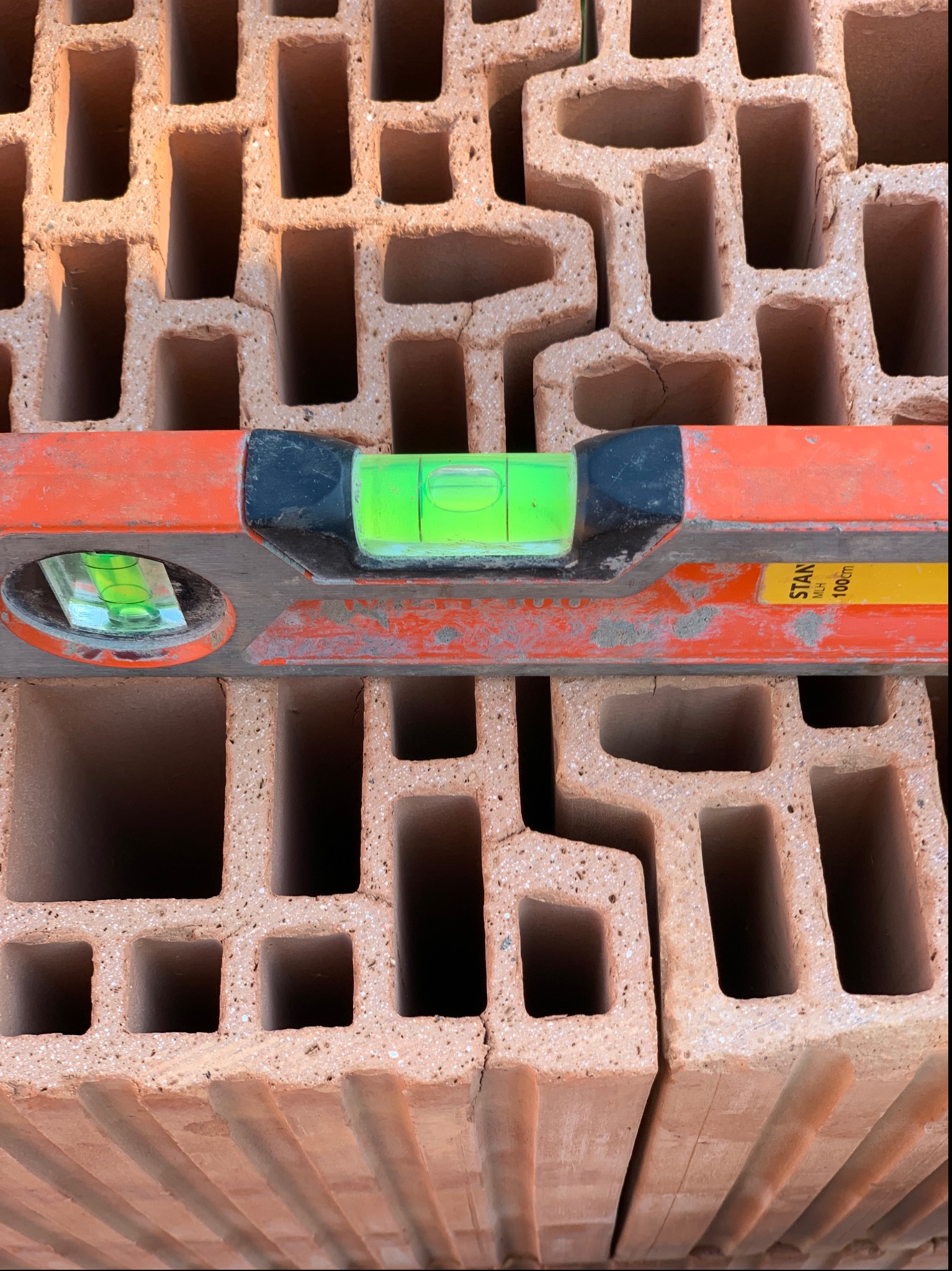 Ułożone bloczki ceramiczne z widoczną poziomicą Stanley MLH 100cm, sprawdzającą ich wypoziomowanie.