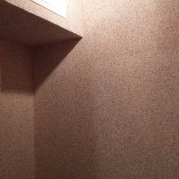 budobel.pl - Fragment wnętrza z beżową, teksturowaną ścianą, białą klapą rewizyjną i wnęką.