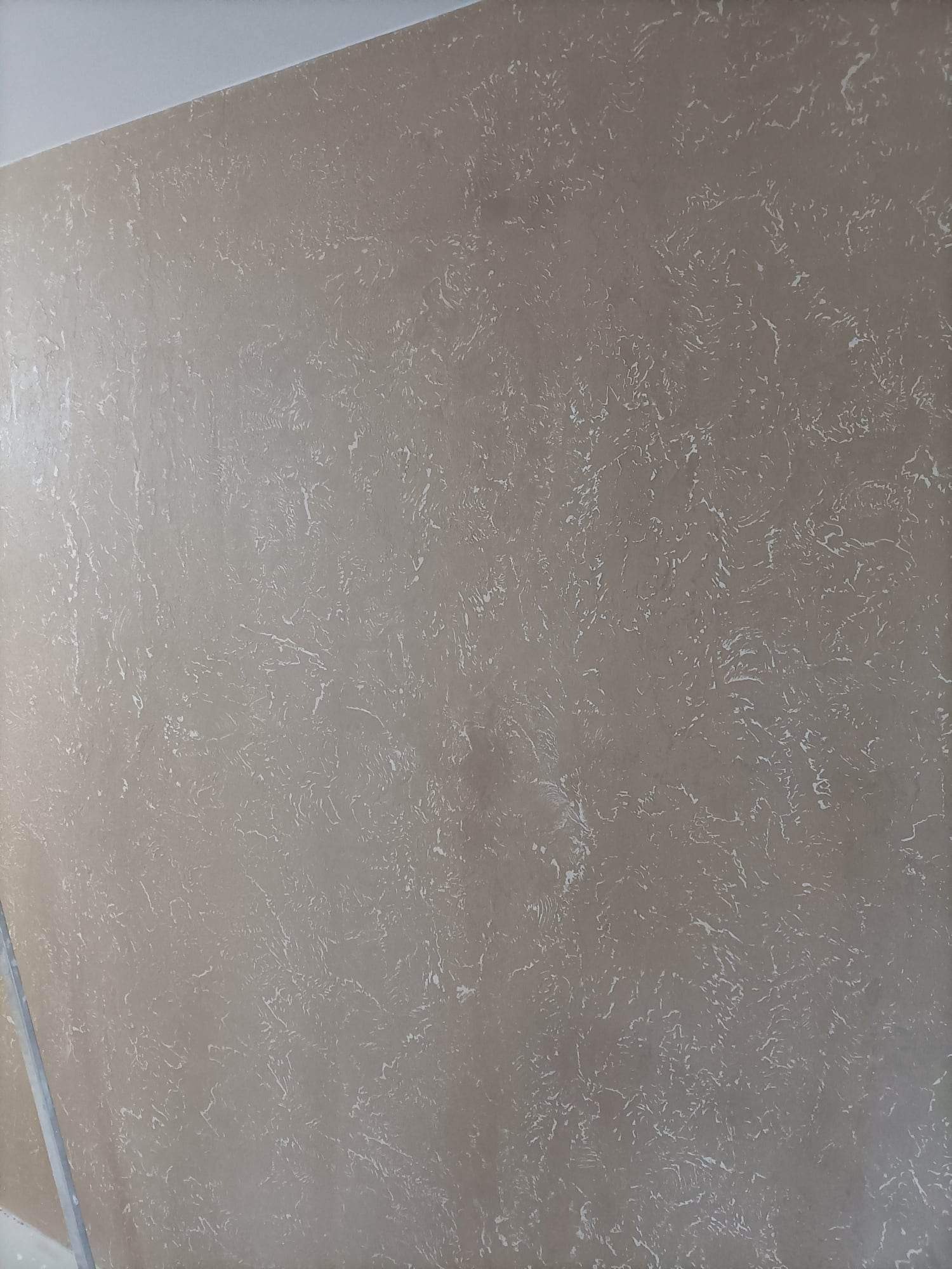 Beżowa ściana z dekoracyjnym wzorem przypominającym marmur, świeżo po malowaniu, widoczne przejścia kolorystyczne i delikatna faktura.