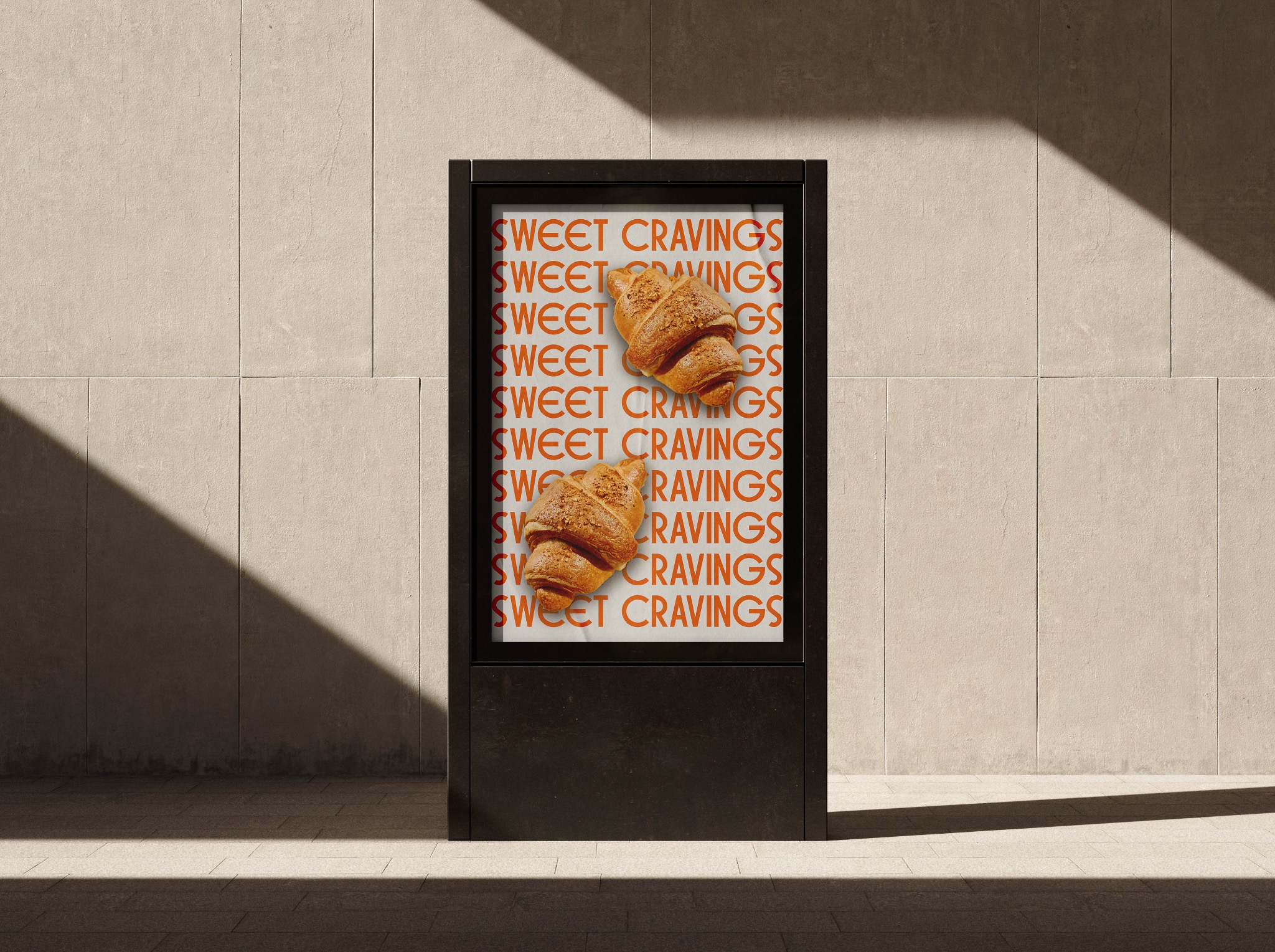 Billboard z reklamą croissantów i napisem 'Sweet Cravings' na tle beżowej ściany w cieniu.