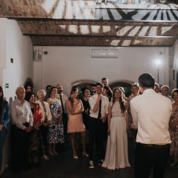 Dj Piter Pan Beatbox - Sala z ceglanym sklepieniem wypełniona gośćmi weselnymi, z prezenterem w białej koszuli stojącym tyłem do obiektywu.