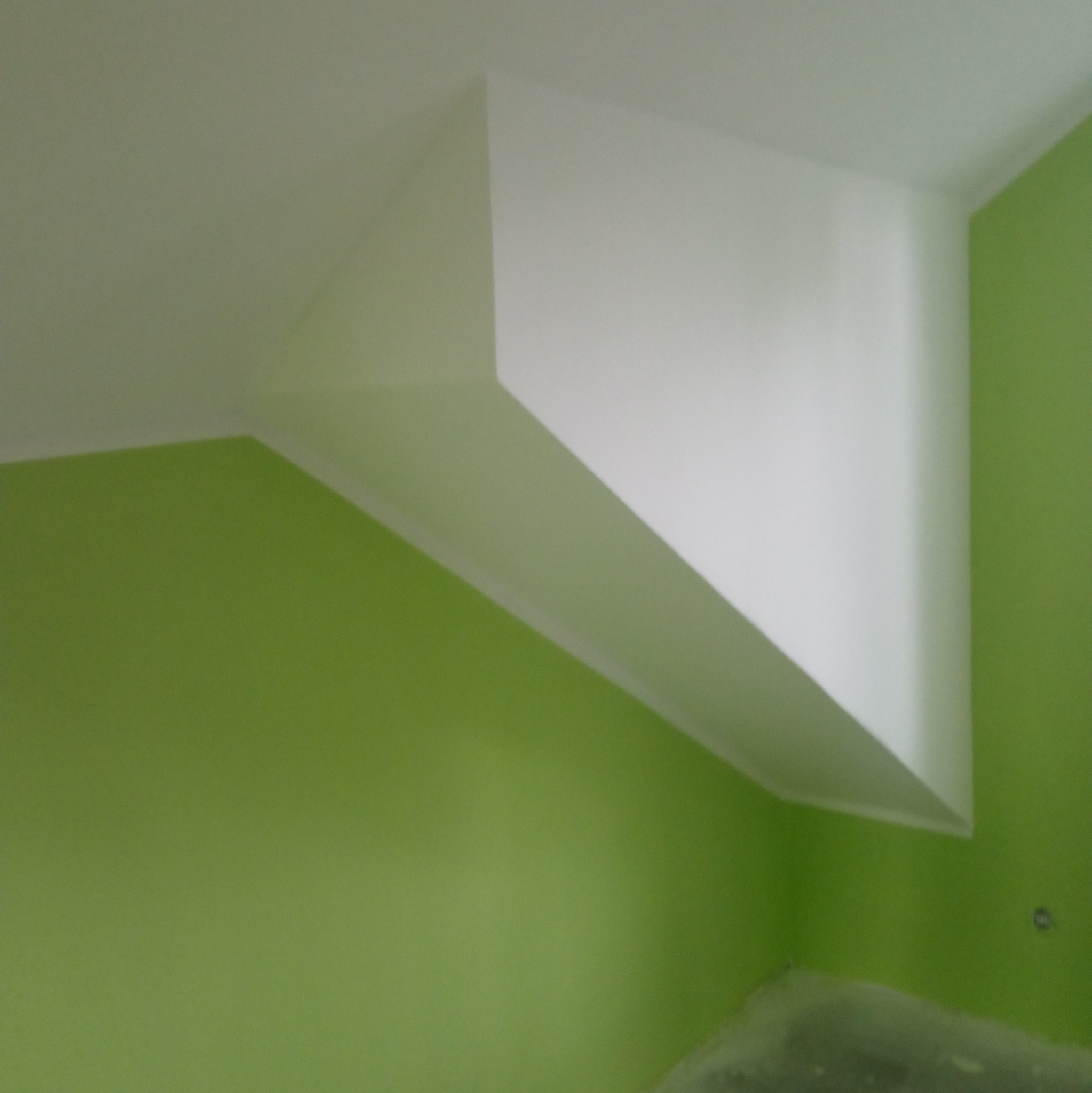 Wnętrze z pomalowaną na zielono ścianą i białym, wystającym fragmentem sufitu w kształcie graniastosłupa.