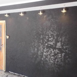 usługi ogólnobudowlane u Ilony - Czarna ściana z dekoracyjnym, srebrzystym wzorem, zabezpieczone drzwi folią malarską, biała listwa podsufitowa z oświetleniem punktowym.