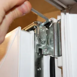 Regulacja okna PCV za pomocą klucza imbusowego na okuciu, widoczne elementy mechanizmu i uszczelka.