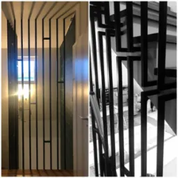 Nowoczesna, czarna metalowa konstrukcja z pionowych prętów, pełniąca funkcję balustrady lub ścianki działowej w jasnym wnętrzu, z widocznym oknem i fragmentem schodów.