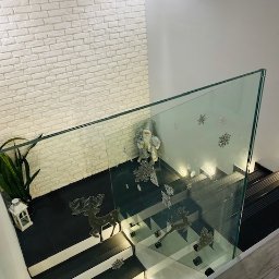 MASTER HOUSE - Szklana balustrada schodowa z motywami reniferów i śnieżynek, biała ceglana ściana w tle, widok z góry.