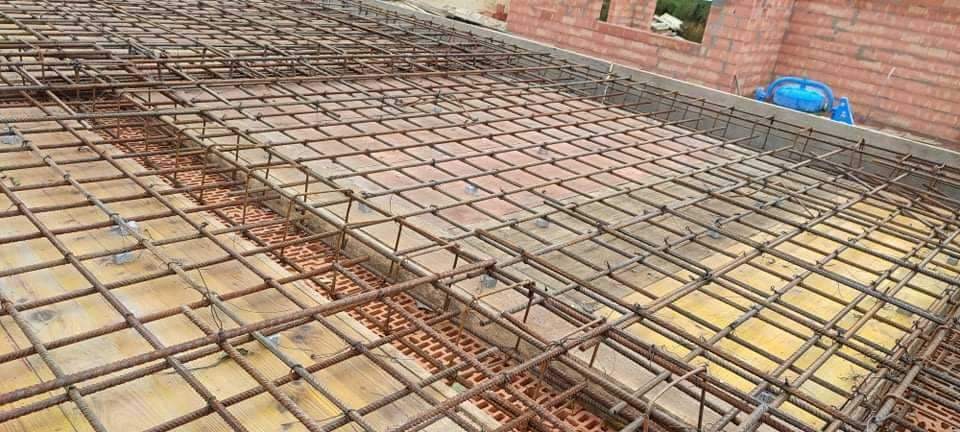 Zbrojenie stropu na deskowaniu z widocznymi pustakami ceramicznymi w tle, przygotowane do zalania betonem.