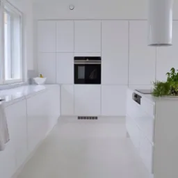 Minimalistyczna, całkowicie biała kuchnia z zabudową meblową bez uchwytów, wyspą kuchenną i okrągłym okapem cylindrycznym