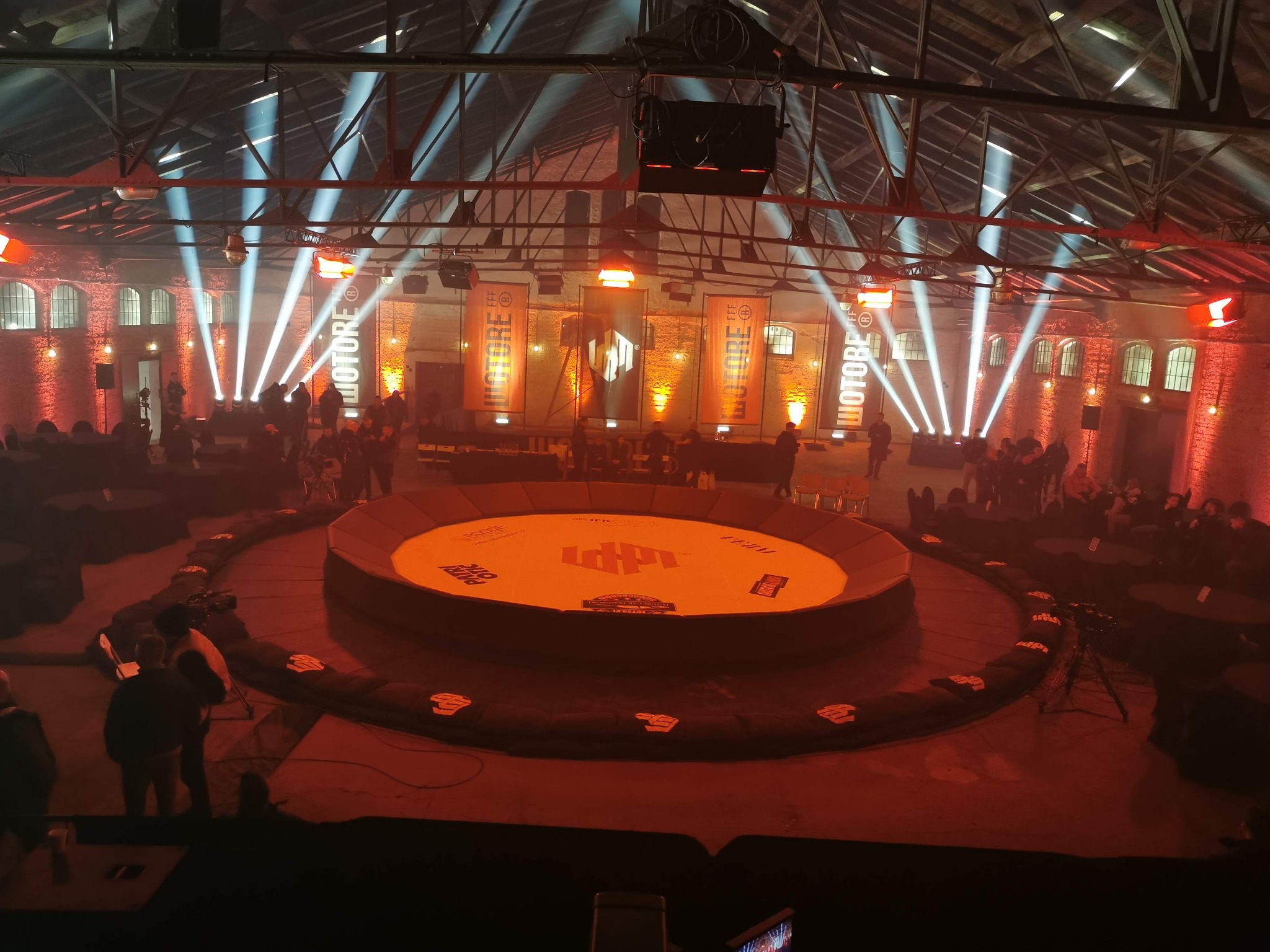 Widok z góry na arenę walk WOTORE w Warszawie, z intensywnym oświetleniem punktowym i dekoracyjnymi banerami. W Katowicach firma oferuje kompleksową organizację podobnych wydarzeń.