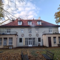 Hydro - Prace na wysokościach w Wejherowie: Pracownik na podnośniku koszowym czyści dach budynku z czerwonej dachówki, unosząc parę wodną, widoczne trzy lukarny.