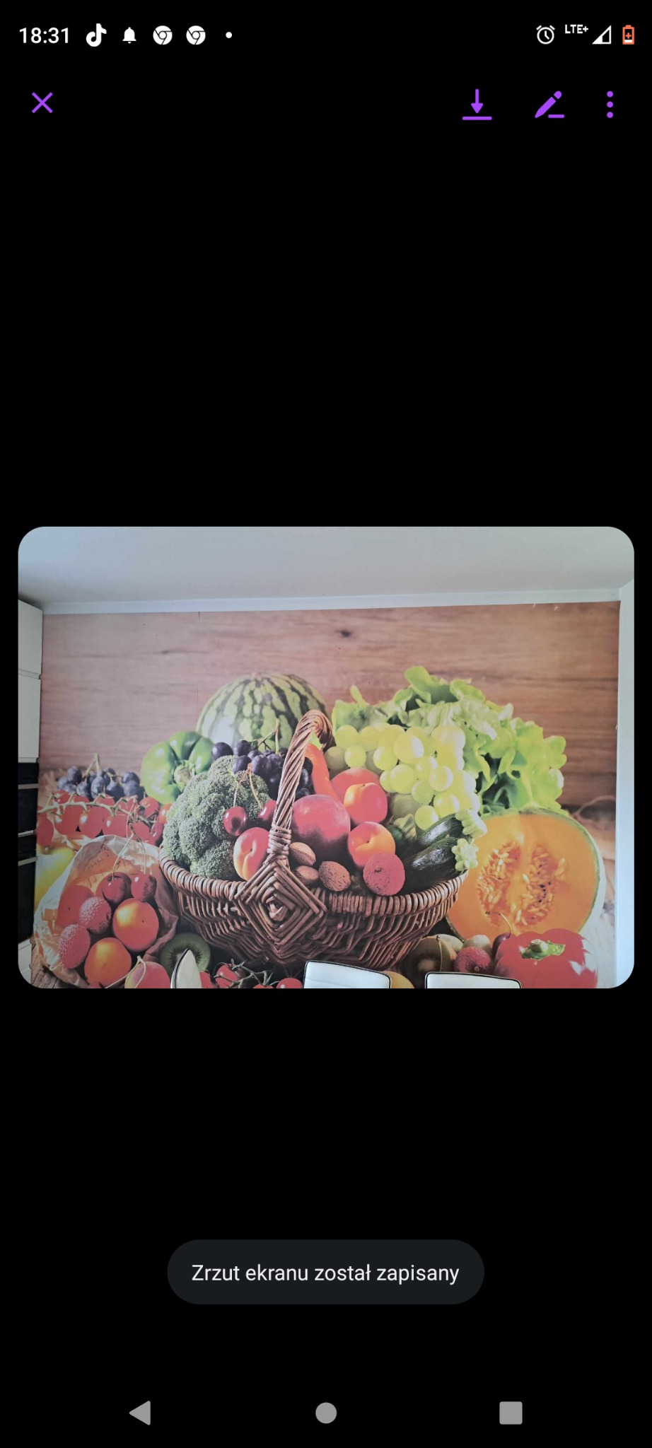 Fototapeta z motywem kosza pełnego owoców i warzyw na drewnianym tle w kuchni.