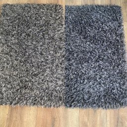 Wporzadku - usługi sprzątania Monika Pająk - Dwa puszyste dywany shaggy, jeden w odcieniach szarości, drugi ciemniejszy, leżące obok siebie na panelach podłogowych.