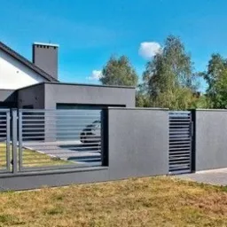 Nowoczesna, przesuwna brama wjazdowa z poziomymi panelami, w kolorze grafitowym, zintegrowana z ogrodzeniem na tle domu z białą elewacją i grafitowym garażem.