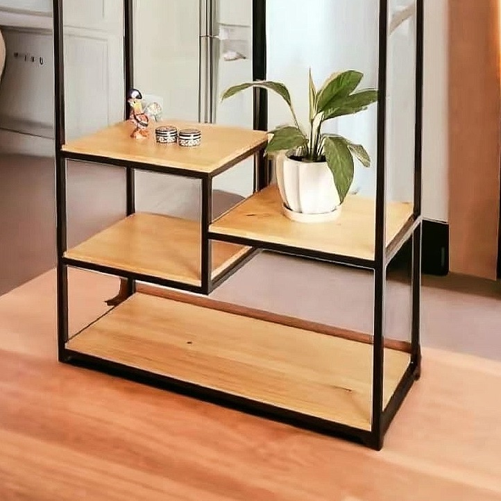 Metalowy regał z drewnianymi półkami w stylu industrialnym, z dekoracjami i rośliną doniczkową, ustawiony na drewnianej podłodze.