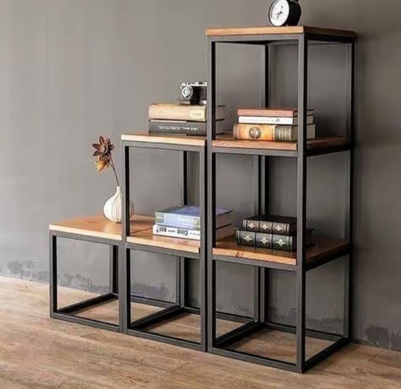 Metalowa konstrukcja regału schodkowego z drewnianymi półkami, styl industrialny, na półkach książki, aparat fotograficzny i zegar.
