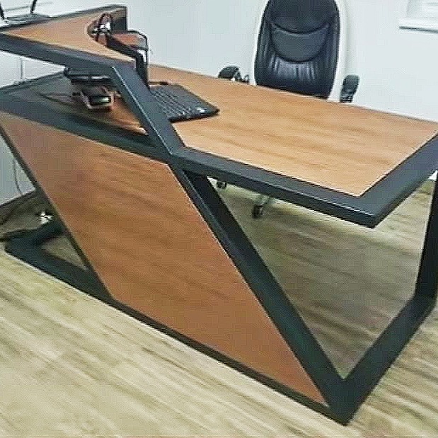 Nowoczesne biurko z blatem z jasnego drewna i czarną metalową konstrukcją, widoczne biurowe krzesło w tle.