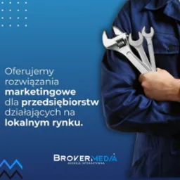 Mężczyzna w niebieskim kombinezonie trzyma zestaw kluczy francuskich na tle reklamy agencji interaktywnej oferującej rozwiązania marketingowe dla firm lokalnych.