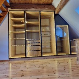NOWY WYMIAR MEBLI AGATA PIECHOTA - Drewniana zabudowa wnęki na poddaszu z szafami z oświetleniem LED, widoczne półki i szuflady, podłoga z jasnego drewna.