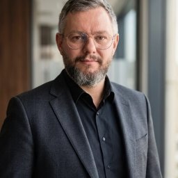 NSNP Grzegorz Piątek - Portret mężczyzny w okularach i garniturze, Środa Wielkopolska. Profesjonalny wizerunek doradcy finansowego lub brokera ubezpieczeniowego, patrzącego wprost.