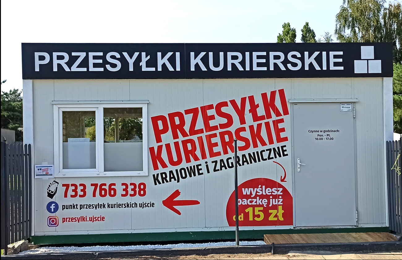 Kontener biurowy z dużym czerwonym napisem 'Przesyłki Kurierskie krajowe i zagraniczne', numerem telefonu i informacją o cenie wysyłki paczki od 15 zł, okno z widocznym wnętrzem i godziny otwarcia...