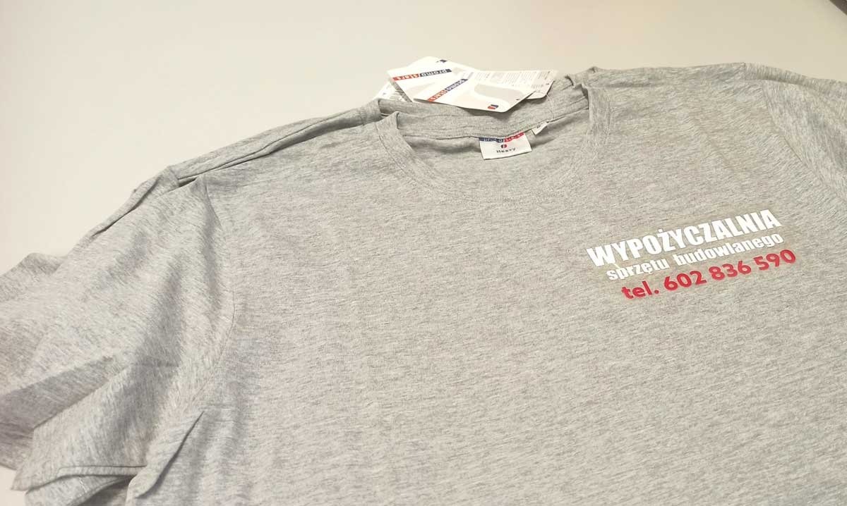 Szara koszulka z nadrukowanym białym napisem 'WYPOŻYCZALNIA sprzętu budowlanego' i czerwonym numerem telefonu 602 836 590.