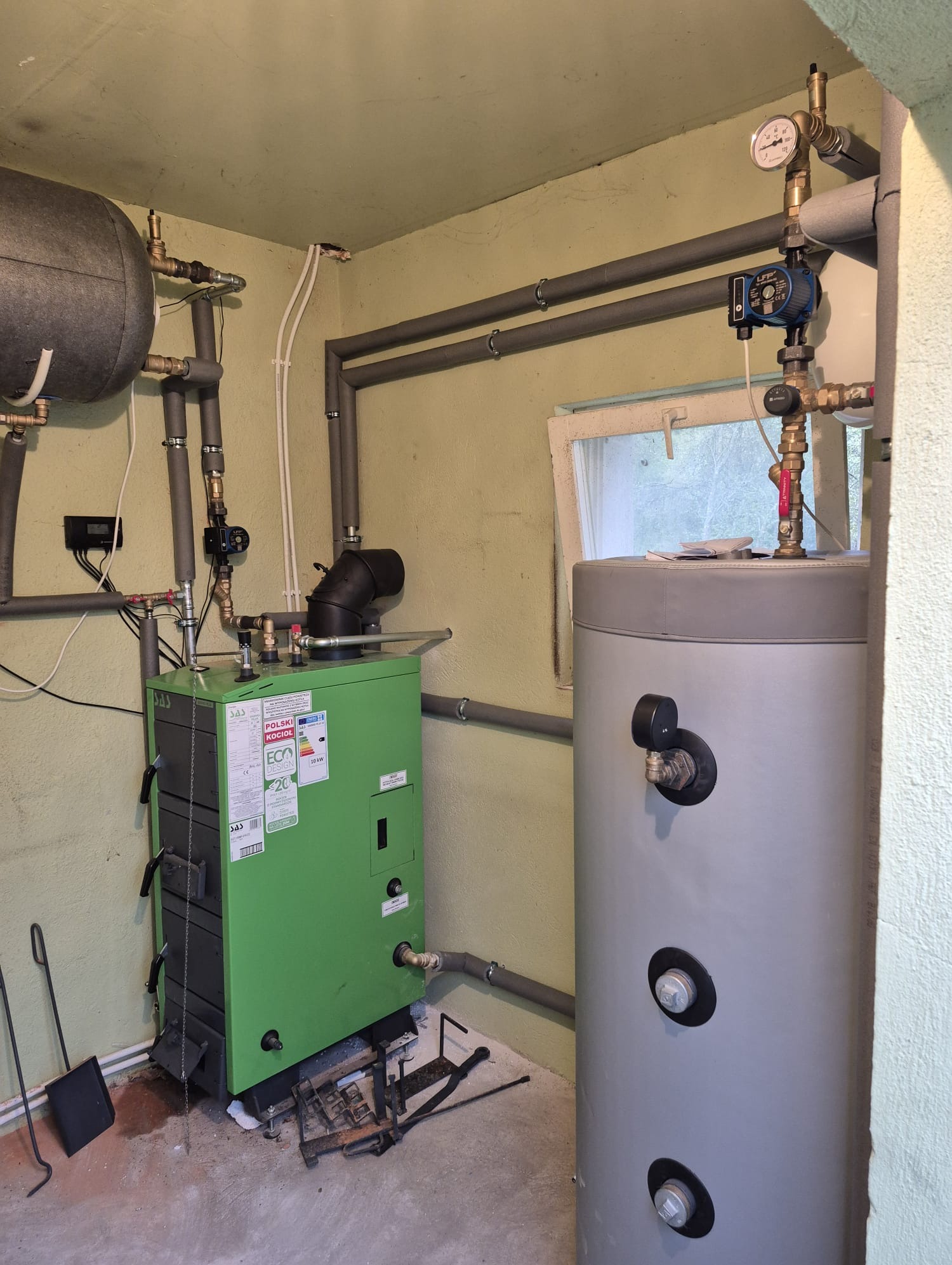 Zmontowana kotłownia z zielonym kotłem zgazowującym drewno SAS Varmo Plus 10 kW, zbiornikiem buforowym 400l i CWU 120l. Instalacja grzewcza w pomieszczeniu.