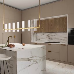 Pod Klucz Agata Malinowska - Nowoczesna kuchnia w beżach z marmurową wyspą, złotą armaturą i wiszącą lampą z mlecznymi kloszami. Na blacie wyspy leżą orzechy włoskie i gałązka z liśćmi.