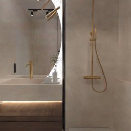 Pod Klucz Agata Malinowska - Nowoczesna łazienka z beżowymi ścianami, złotą armaturą i deszczownicą, podświetlaną szafką pod umywalką i dekoracyjnym oświetleniem sufitowym