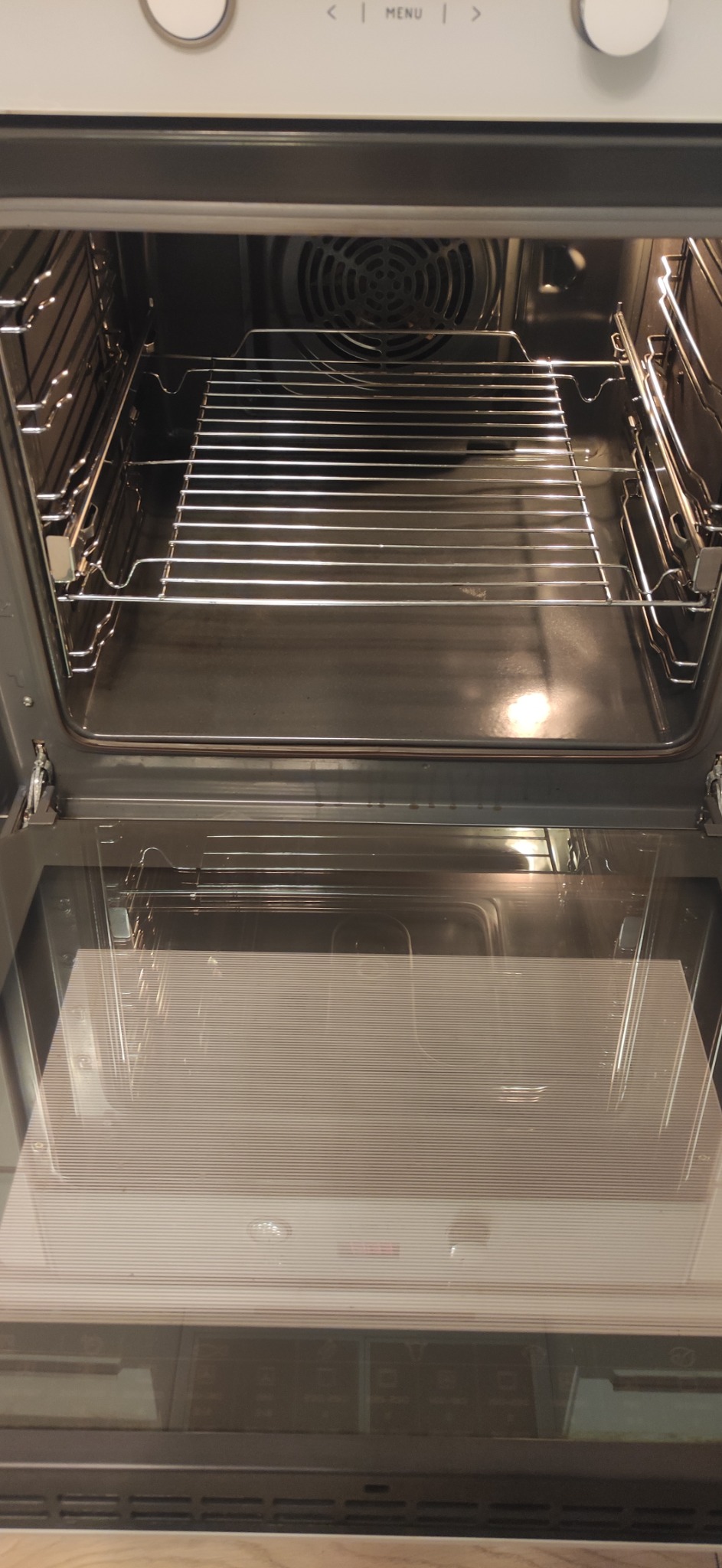 Wnętrze piekarnika elektrycznego z metalową kratką i szklanymi drzwiczkami, widoczne ślady użytkowania.