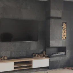 Ściana z szarej płytki imitującej kamień z wbudowanym kominkiem, półką na drewno i telewizorem. Na szafce RTV stoi kolekcja figurek trolli.