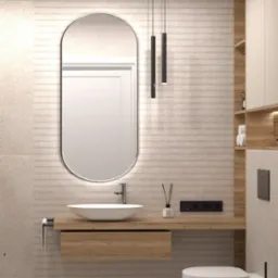 Nowoczesna łazienka w beżowej kolorystyce z umywalką nablatową, owalnym lustrem z podświetleniem LED, wiszącą toaletą i drewnopodobną szafką pod umywalką oraz półkami.