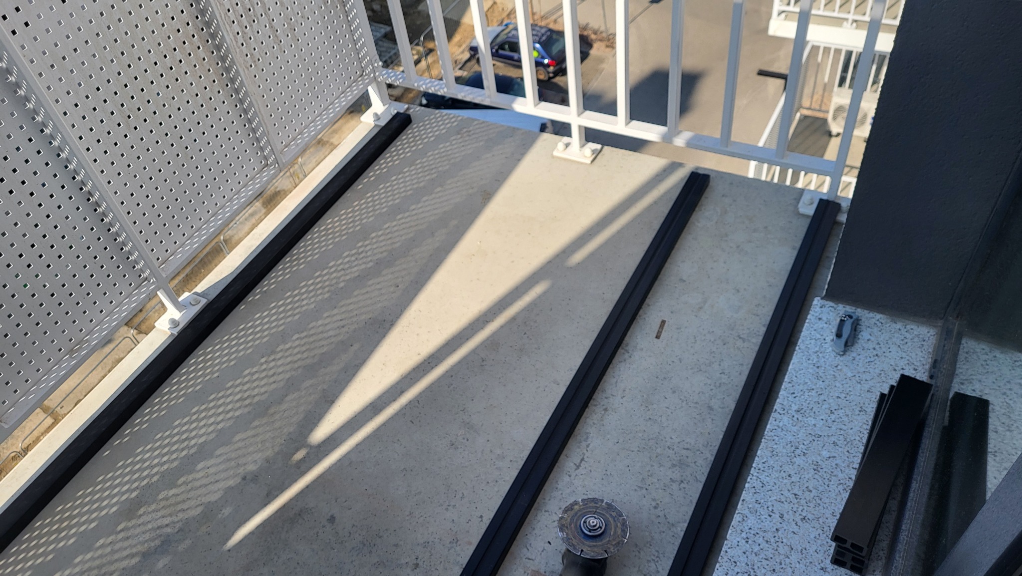 Montaż podkonstrukcji na balkonie we Wrocławiu. Widoczne profile, narzędzia i cień. Przygotowanie do ułożenia desek na balkonie.