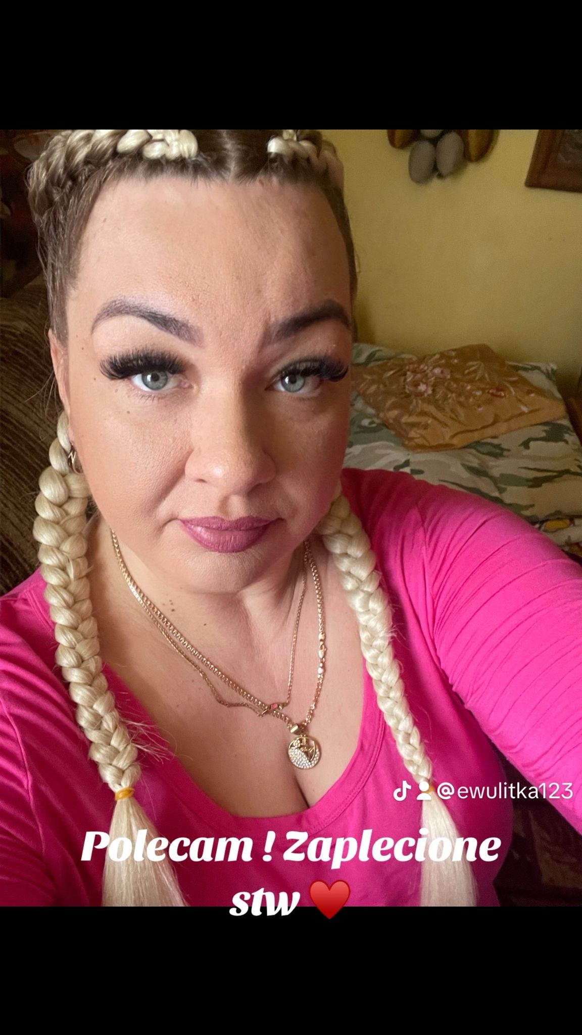 Selfie kobiety z blond warkoczami, widoczne detale fryzury i makijażu, w tym długie rzęsy i biżuteria.