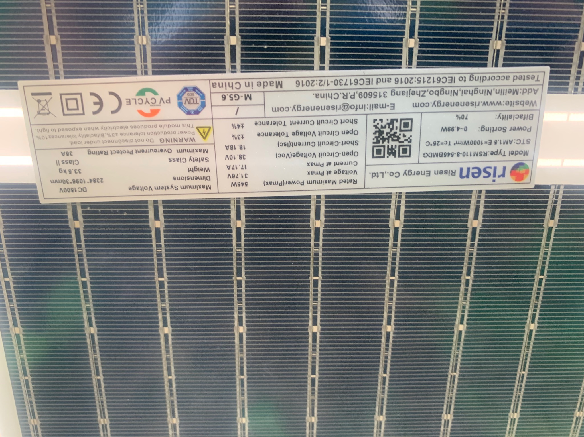 Szczegółowy widok modułu fotowoltaicznego Risen Energy RSM110-8-545BMDG z widoczną etykietą specyfikacji technicznej, w tym moc 545W, napięcie 38.10V i prąd 18.18A, wyprodukowany w Chinach zgodnie...
