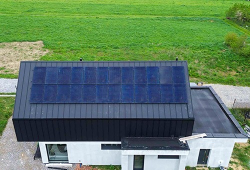 Widok z góry na dom z panelami słonecznymi Longi 525W (18 sztuk) zainstalowanymi na dachu pokrytym dachówką ceramiczną z wykorzystaniem haków typu S, z falownikiem Huawei SUN2000-10KTL-M1, na tle...