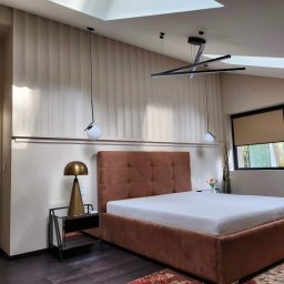 BrytanBudownictwo - Nowoczesna sypialnia w beżach i brązach: tapicerowane łóżko, pionowe panele ścienne, designerskie lampy wiszące i stolik nocny z lustrzanym blatem.