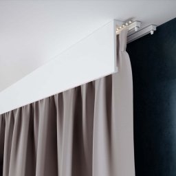 Fabryka Designu - sztukateria, szyny karniszowe, maskownice, firany, zasłony - Ukryta szyna karniszowa z oświetleniem LED i zasłoną w odcieniach szarości na tle ciemnej ściany.