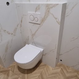 Piotr Szczepkowski usługi budowlane - Nowoczesna toaleta podwieszana z białymi płytkami imitującymi marmur na ścianach i podłogą z płytek w jodełkę.