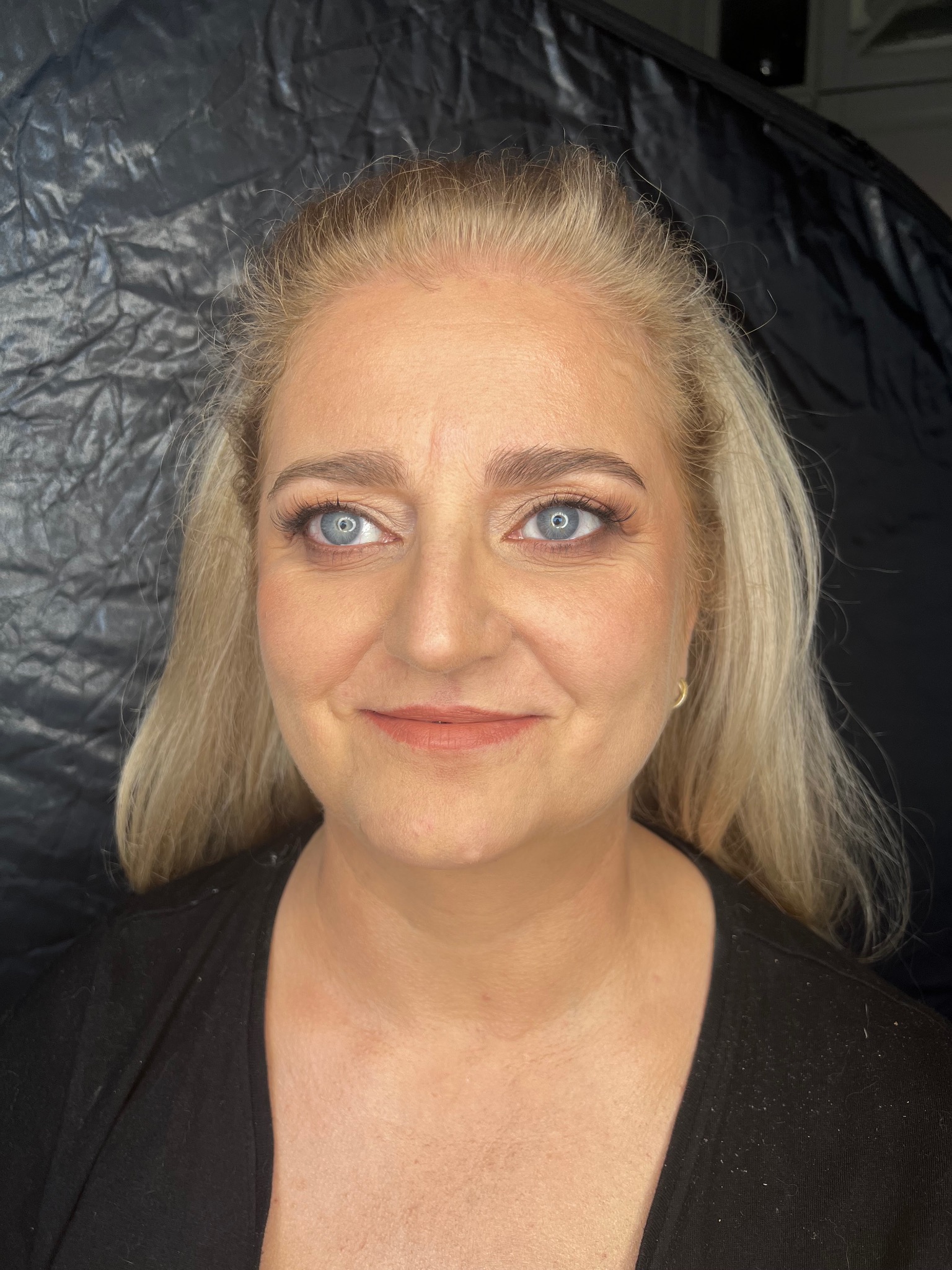 Portret kobiety z delikatnym dziennym makijażem w Gdyni, z wyraźnie podkreślonymi rzęsami i brwiami, na rozmytym czarnym tle.