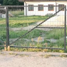 Brama skrzydłowa z wypełnieniem panelowym komponująca się z ogrodzeniem.